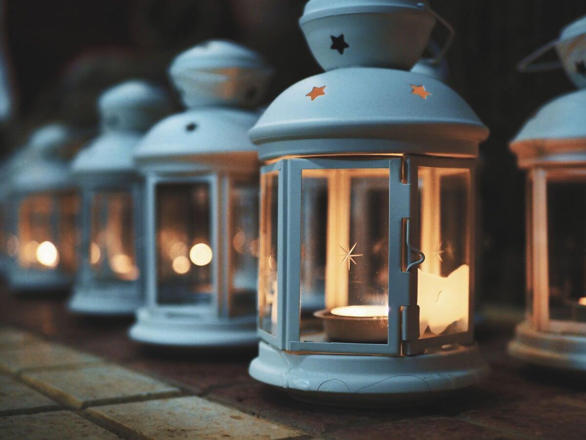 several white lanterns lit with tea light candles looks like a winter or Christmas event